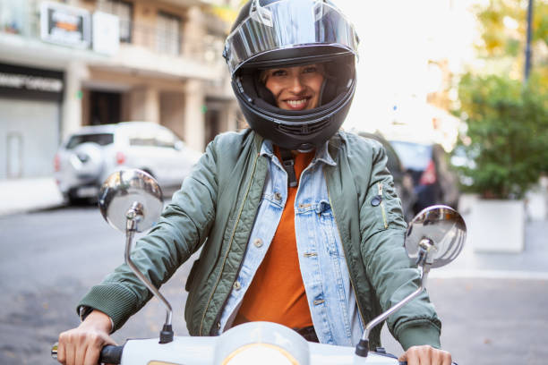 Cheerful woman wearing crash helmet sitting on motorbike outdoors